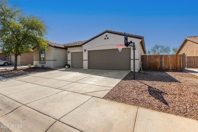 mediterranean / spanish-style home featuring fence, a tile roof, concrete driveway, stucco siding, and an attached garage