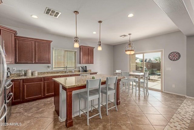 kitchen with tile patterned flooring, a center island, visible vents, and a sink