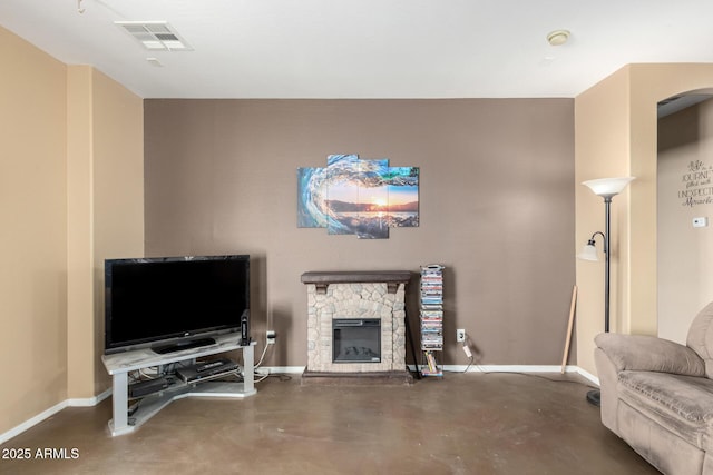 living area with finished concrete flooring, a fireplace, visible vents, and baseboards