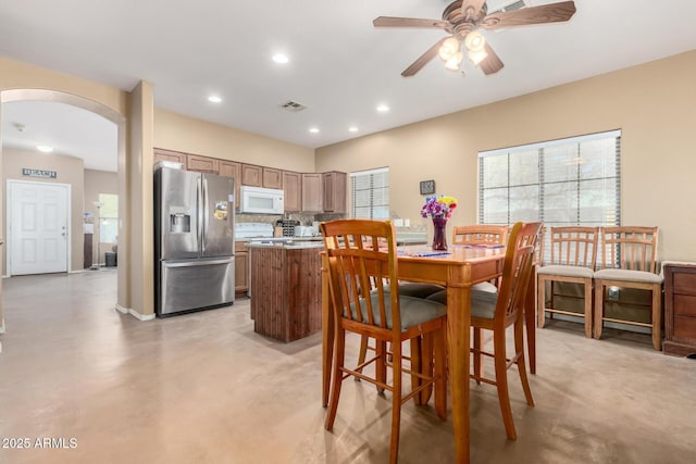 dining area featuring arched walkways, concrete flooring, recessed lighting, visible vents, and a ceiling fan