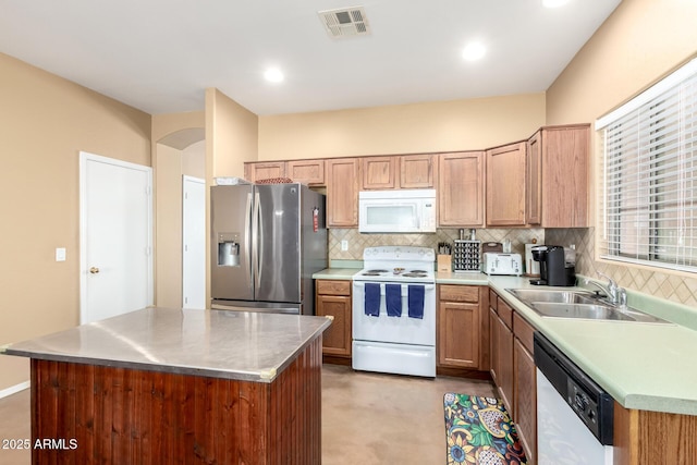 kitchen with white appliances, a sink, a kitchen island, visible vents, and backsplash