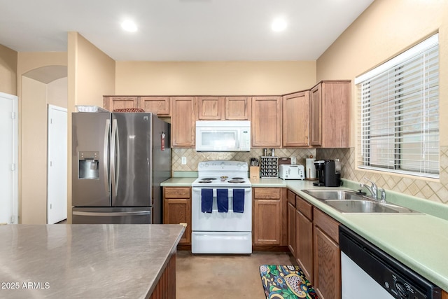 kitchen featuring tasteful backsplash, white appliances, light countertops, and a sink