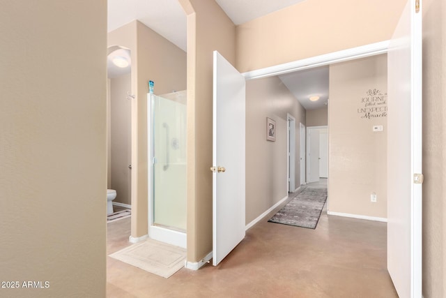 hall with finished concrete floors and baseboards