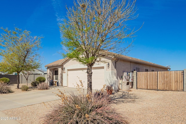 view of front of home featuring a garage, fence, driveway, and stucco siding