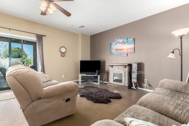 living area featuring ceiling fan, a stone fireplace, visible vents, baseboards, and finished concrete flooring