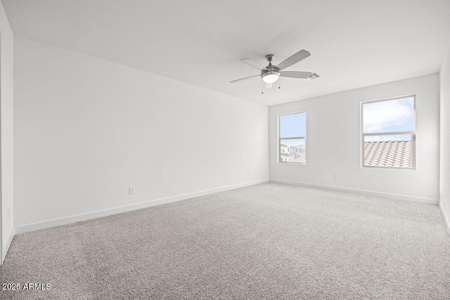 carpeted empty room with ceiling fan and baseboards