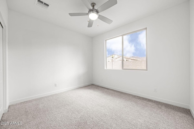 carpeted spare room with ceiling fan, visible vents, and baseboards