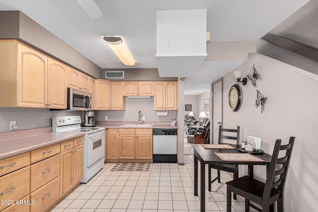 kitchen with sink, light tile patterned floors, white appliances, and light brown cabinets