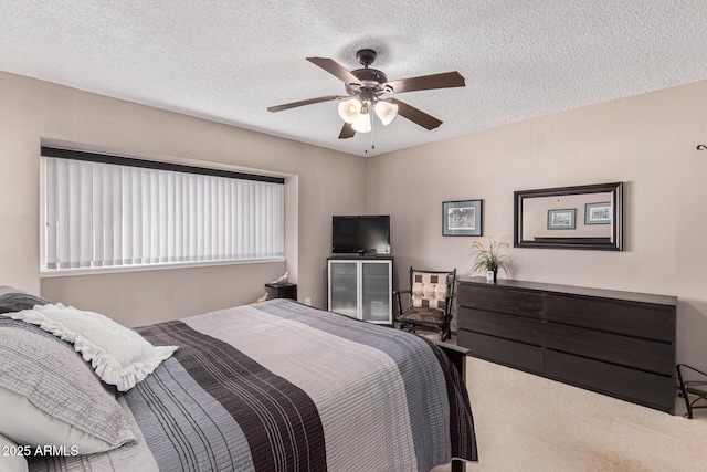 bedroom with ceiling fan, carpet, and a textured ceiling