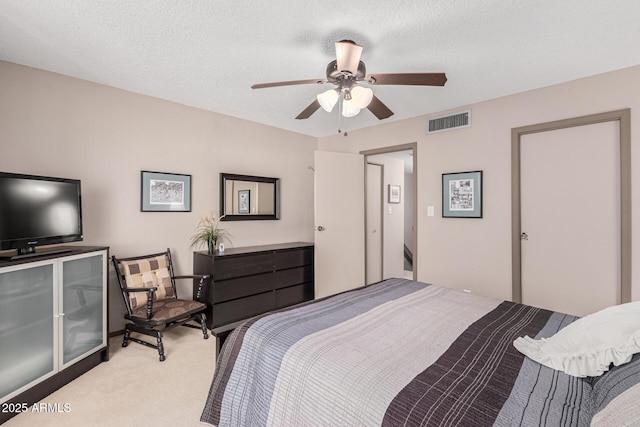 bedroom with a textured ceiling, light colored carpet, and ceiling fan