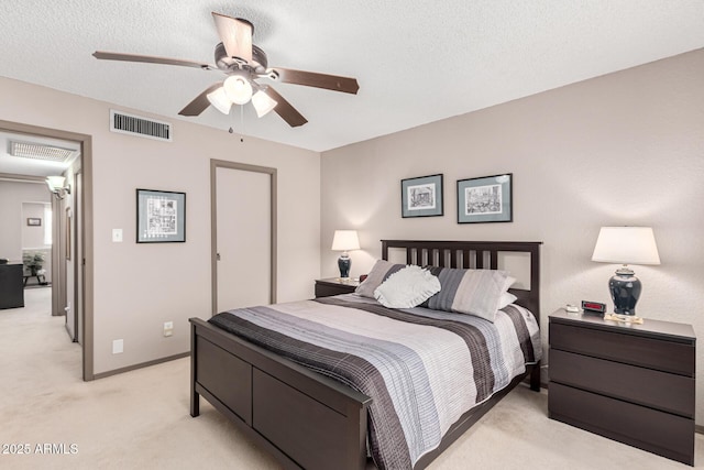 bedroom featuring ceiling fan, light colored carpet, and a textured ceiling