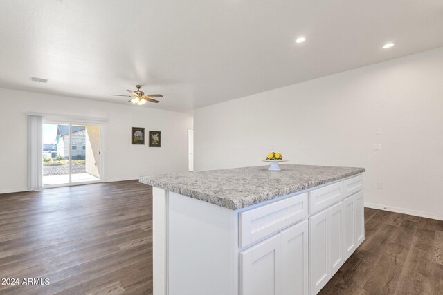 kitchen with white cabinets, light stone countertops, dark wood-type flooring, ceiling fan, and a kitchen island