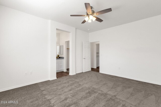 unfurnished bedroom with dark carpet, ceiling fan, and connected bathroom