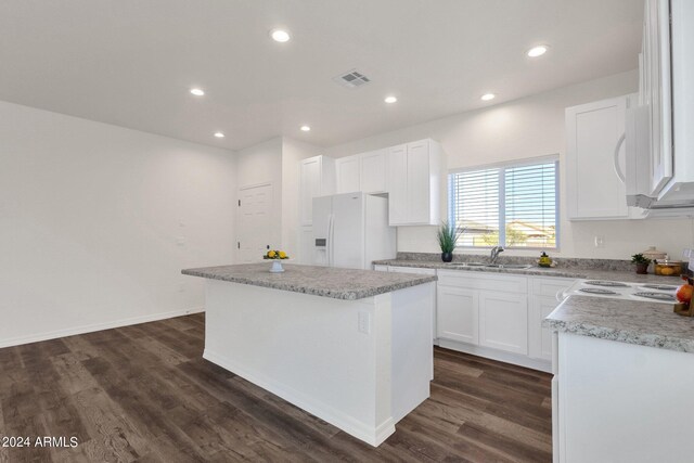 kitchen featuring a kitchen island, light stone countertops, white appliances, dark wood-type flooring, and white cabinets