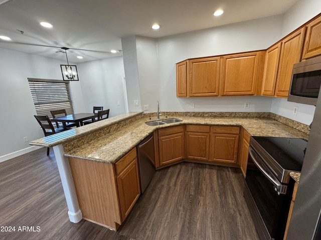 kitchen featuring dark hardwood / wood-style floors, sink, kitchen peninsula, appliances with stainless steel finishes, and decorative light fixtures