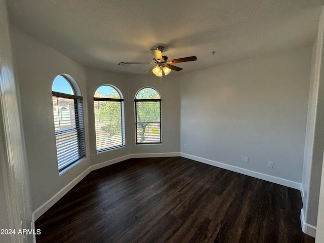 empty room with dark hardwood / wood-style flooring, a textured ceiling, and ceiling fan