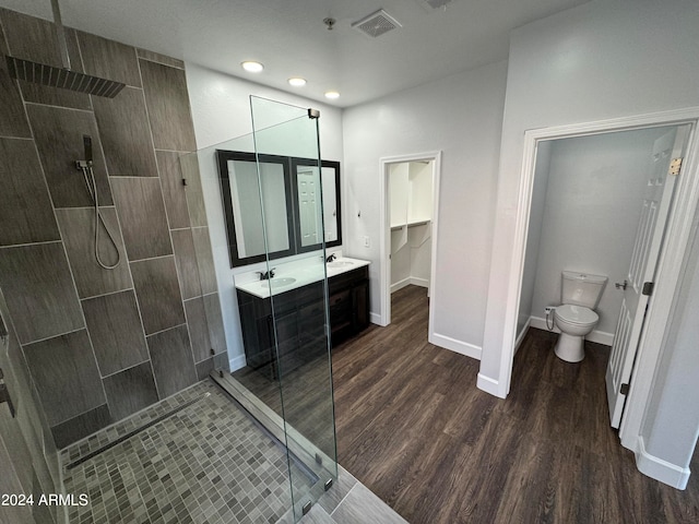 bathroom with a tile shower, hardwood / wood-style floors, vanity, and toilet