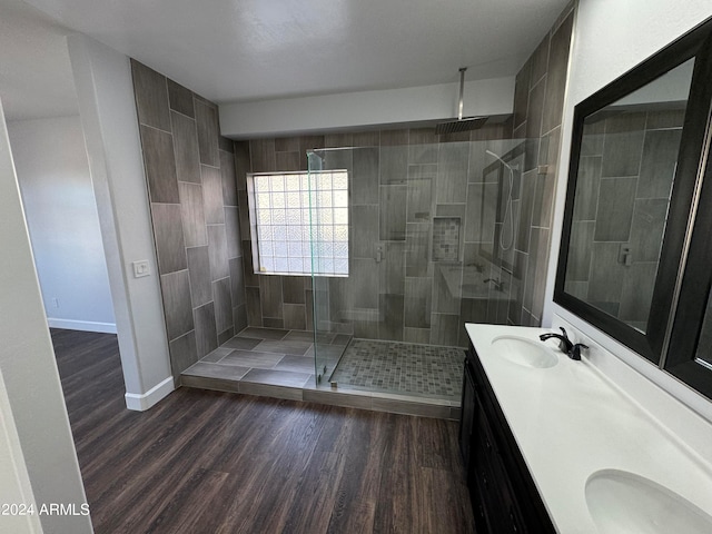 bathroom with hardwood / wood-style flooring, tiled shower, and vanity