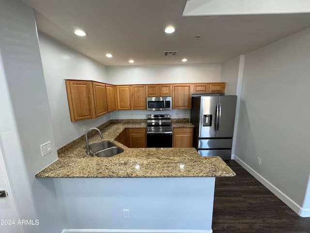 kitchen with light stone countertops, appliances with stainless steel finishes, sink, and kitchen peninsula