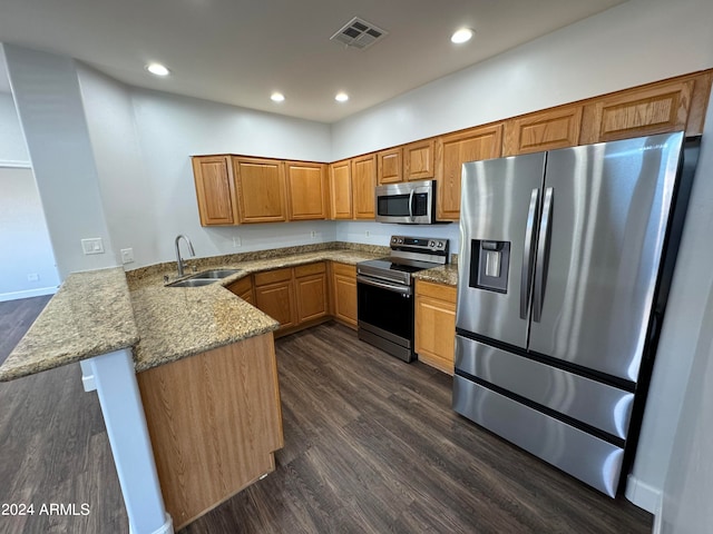 kitchen with sink, light stone counters, stainless steel appliances, kitchen peninsula, and dark hardwood / wood-style floors