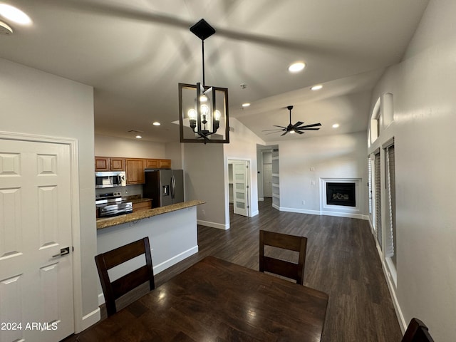 kitchen featuring decorative light fixtures, vaulted ceiling, appliances with stainless steel finishes, and dark wood-type flooring