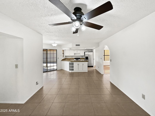 12342 S Shoshoni Dr, Phoenix, AZ 85044 - unfurnished living room featuring a textured ceiling, ceiling fan, tile patterned flooring, arched walkways, and baseboards