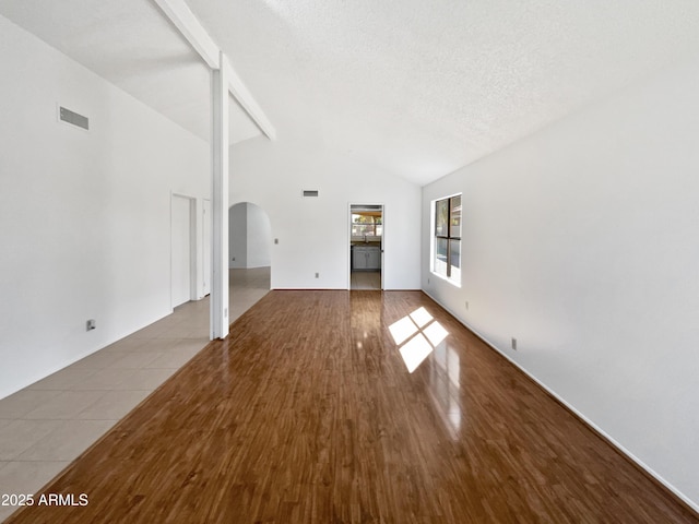12342 S Shoshoni Dr, Phoenix, AZ 85044 - unfurnished living room with arched walkways, lofted ceiling, wood finished floors, and a textured ceiling