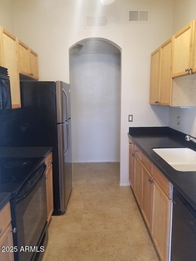 kitchen featuring light brown cabinets, black appliances, and visible vents