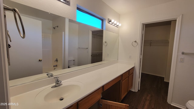full bathroom featuring shower / bath combination, wood finished floors, vanity, toilet, and a spacious closet