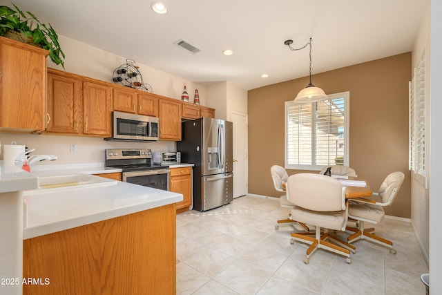 kitchen with light tile patterned floors, appliances with stainless steel finishes, sink, and pendant lighting