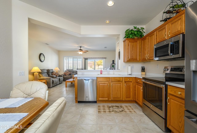 kitchen featuring ceiling fan, kitchen peninsula, sink, appliances with stainless steel finishes, and light tile patterned floors