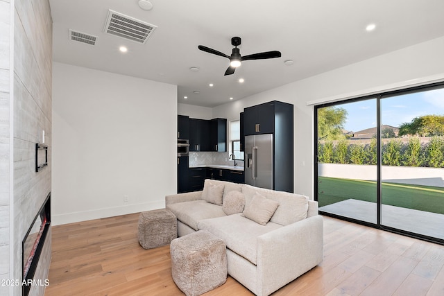 1013 W Ardmore Rd, Phoenix, AZ 85041 - living room featuring ceiling fan, light wood-style floors, a tiled fireplace, baseboards, and recessed lighting