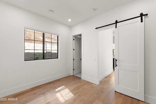 1013 W Ardmore Rd, Phoenix, AZ 85041 - unfurnished bedroom featuring a barn door, baseboards, light wood-style flooring, and recessed lighting