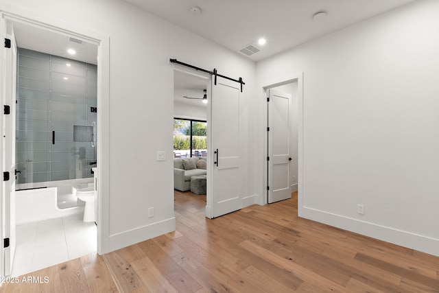 1013 W Ardmore Rd, Phoenix, AZ 85041 - unfurnished bedroom featuring a barn door, baseboards, light wood finished floors, recessed lighting, and ensuite bathroom