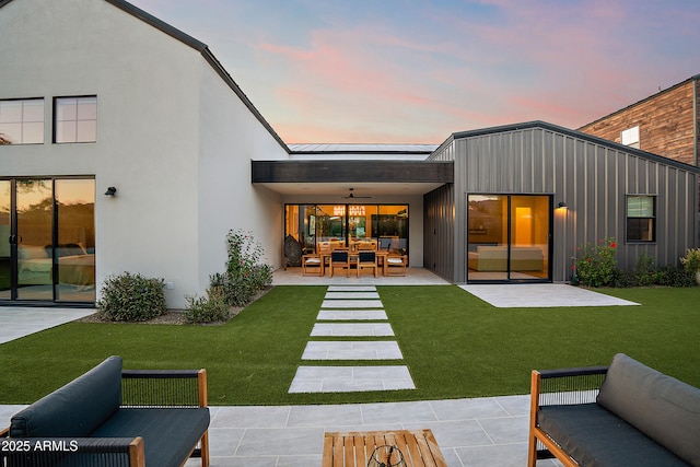 1013 W Ardmore Rd, Phoenix, AZ 85041 - back of house at dusk featuring an outdoor living space, a patio area, ceiling fan, a yard, and stucco siding