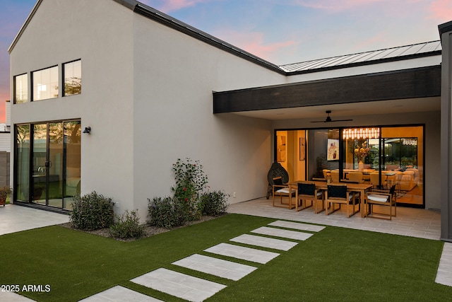 1013 W Ardmore Rd, Phoenix, AZ 85041 - back of property at dusk with a patio, a ceiling fan, a lawn, and a standing seam roof