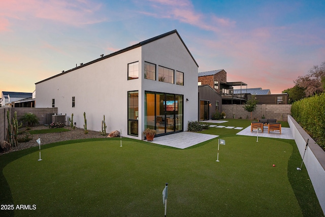1013 W Ardmore Rd, Phoenix, AZ 85041 - back of house at dusk with an area to practice putting, a patio, fence, and stucco siding