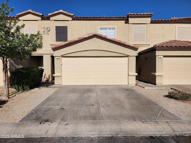 view of front of house featuring a tiled roof, stucco siding, driveway, and a garage
