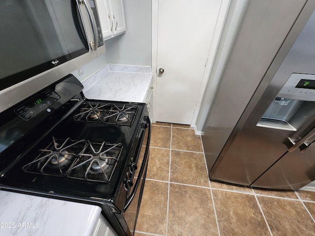 kitchen featuring light countertops, range with gas cooktop, stainless steel microwave, and white cabinetry
