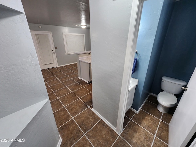 full bathroom with toilet, a textured wall, tile patterned flooring, and vanity