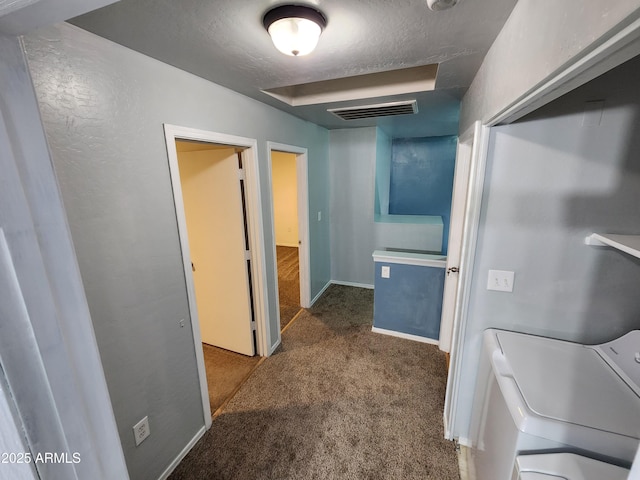 corridor with carpet floors, a textured ceiling, independent washer and dryer, and visible vents