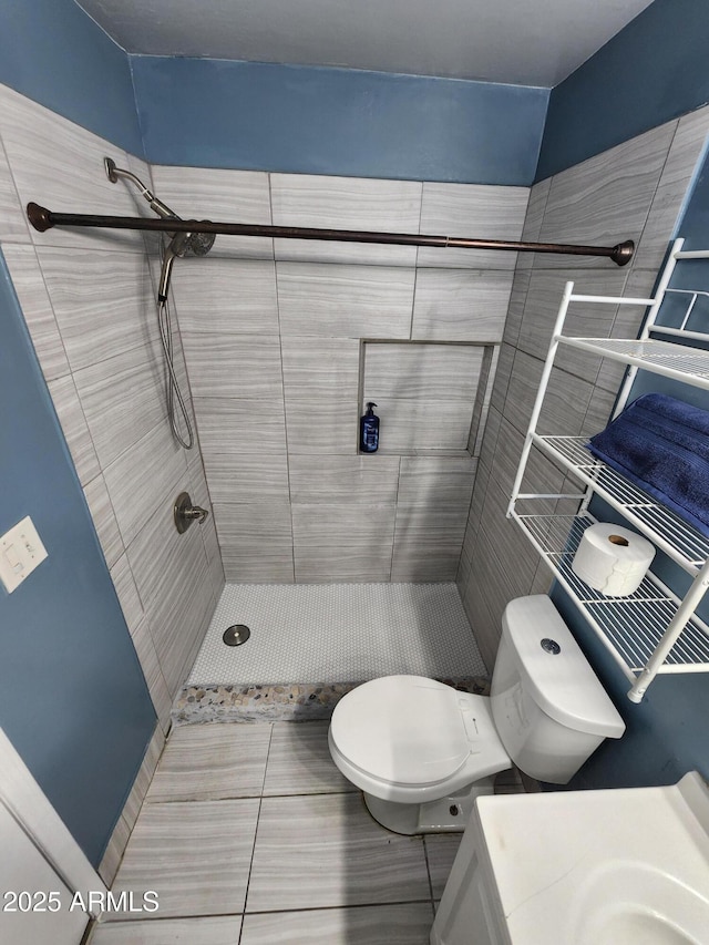 full bathroom featuring vanity, a tile shower, and toilet