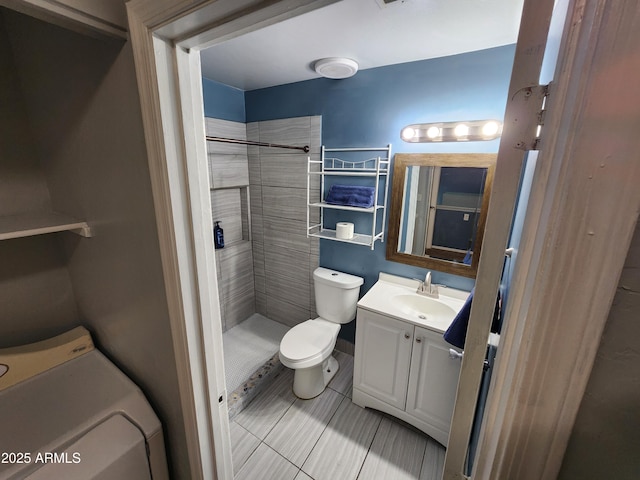 full bathroom featuring tile patterned flooring, vanity, washer / dryer, toilet, and tiled shower
