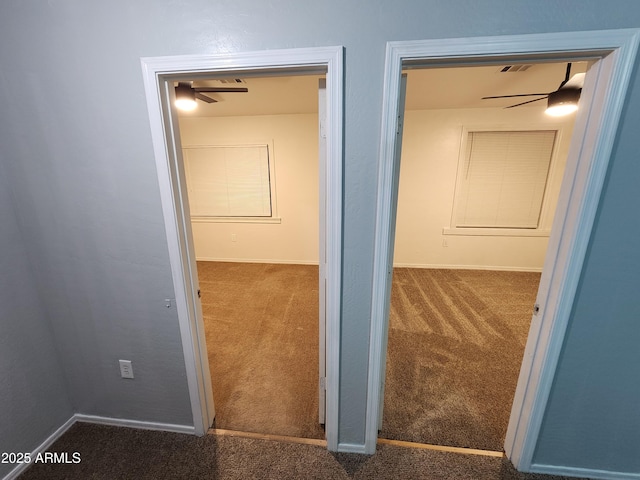 hall featuring baseboards, carpet flooring, and visible vents