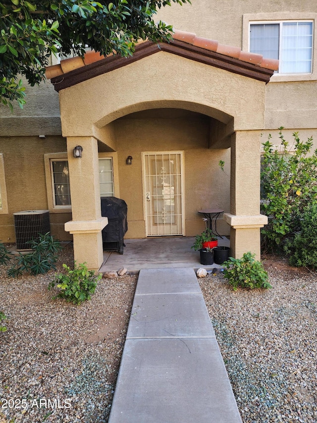 doorway to property with stucco siding and central AC