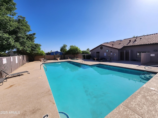 community pool with a fenced backyard and a patio area