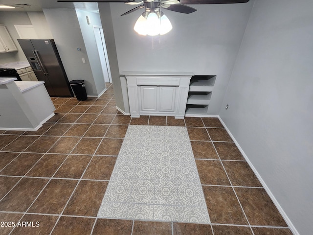 interior space featuring light countertops, stainless steel fridge with ice dispenser, a ceiling fan, and dark tile patterned floors