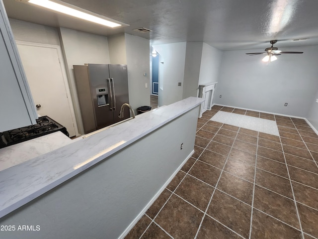 kitchen featuring ceiling fan, light stone countertops, dark tile patterned flooring, stainless steel refrigerator with ice dispenser, and visible vents