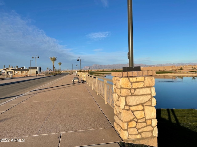 view of road featuring a water and mountain view and street lighting