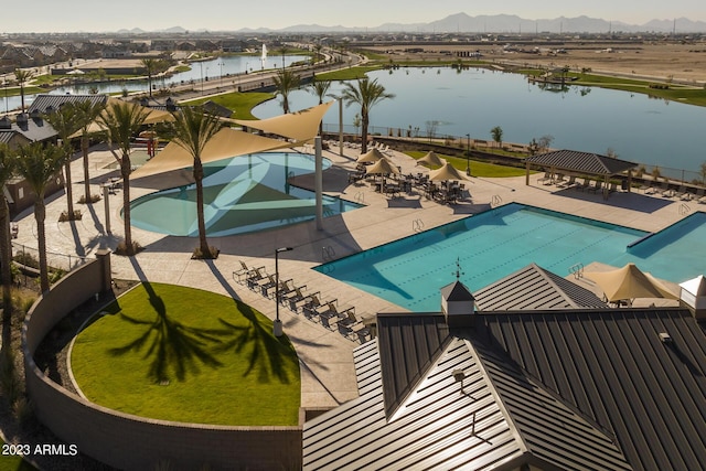 community pool featuring a water view, a patio, and fence